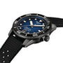 A Tissot Seastar 1000 Powermatic 80 automatic watch with a blue dial, white markers, and a black textured rubber strap is displayed at an angle.