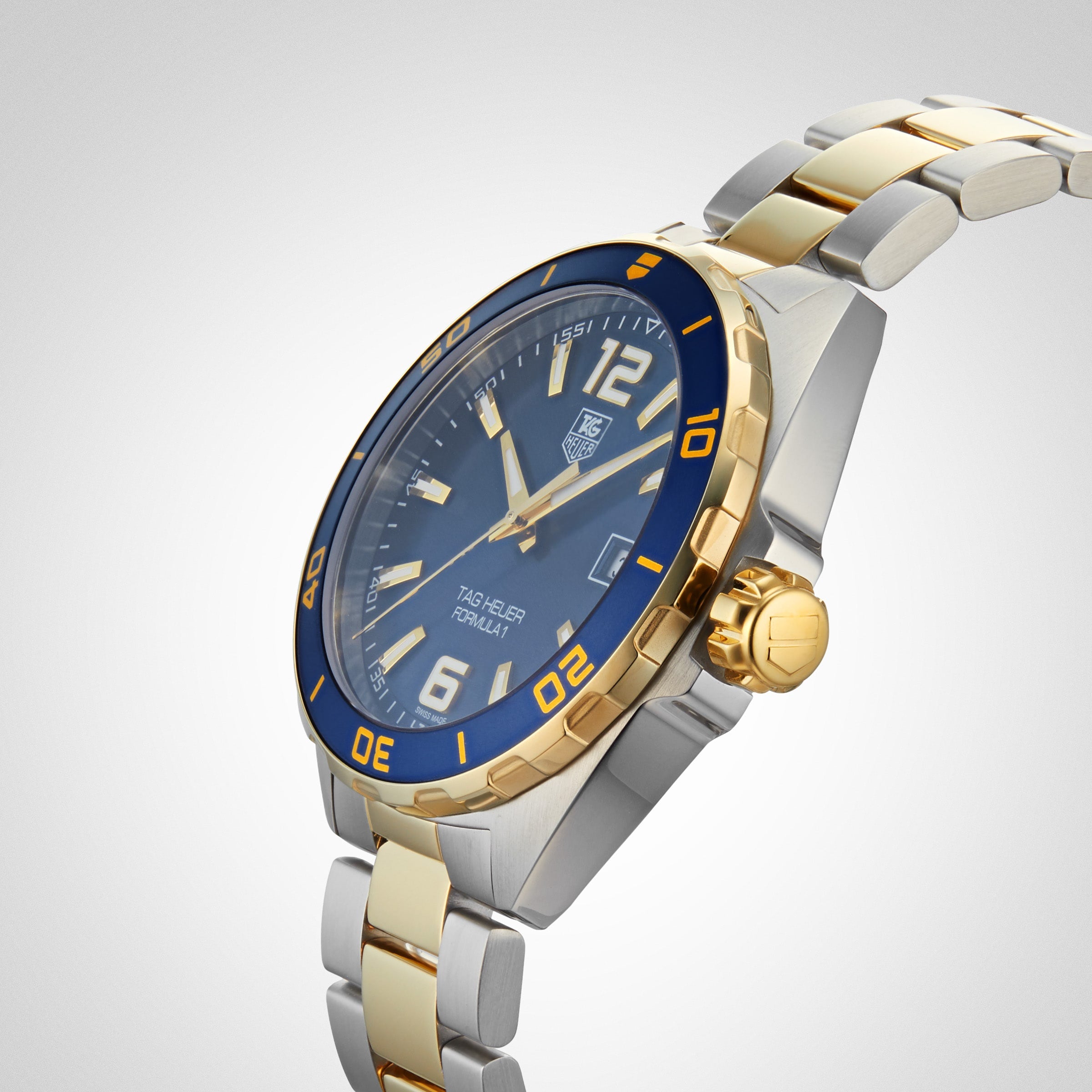 The TAG Heuer Special Edition Formula 1 Date watch features a blue face, gold accents, and a silver-gold metal band, displayed on a light background.