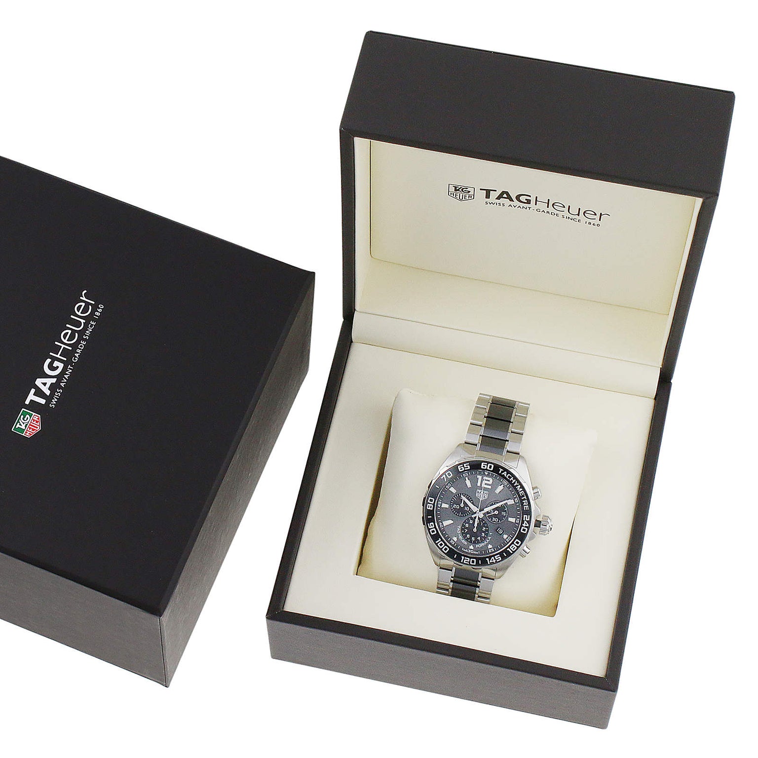 The TAG Heuer Formula 1 Chronograph with a metal band is shown in an open black TAG Heuer box, highlighting its sporty, racing-inspired design, with the box lid and outer packaging also visible.