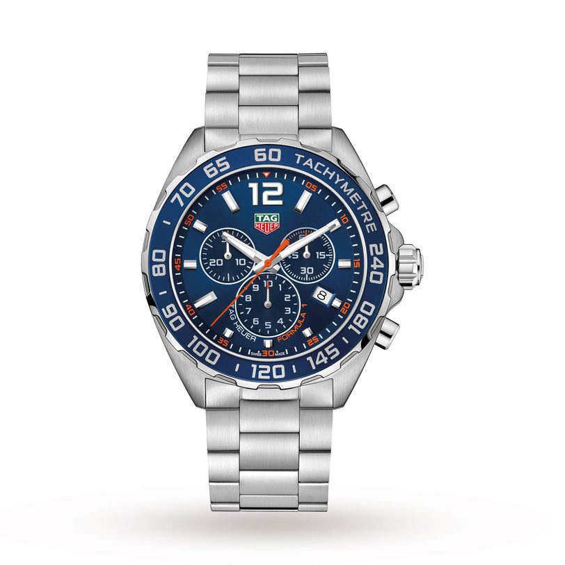The TAG Heuer Formula 1 Chronograph features a stainless steel case, blue tachymeter bezel, quartz movement, three subdials, date display, and silver metal bracelet, displayed on a white background.