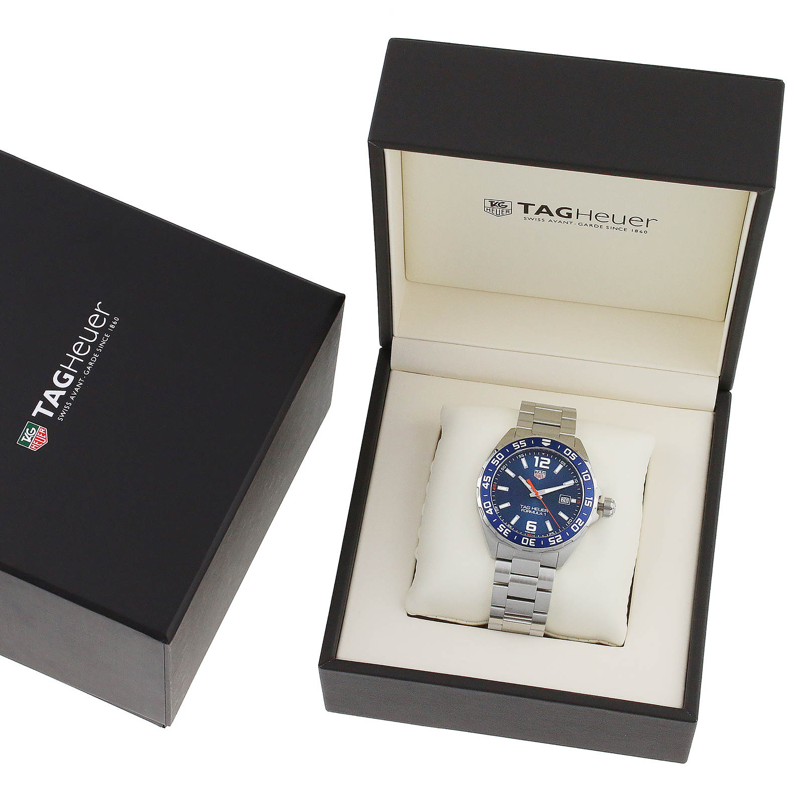 A TAG Heuer Formula 1 Date watch with a blue sunray dial and silver metal band is showcased in an open branded box beside its closed outer packaging.