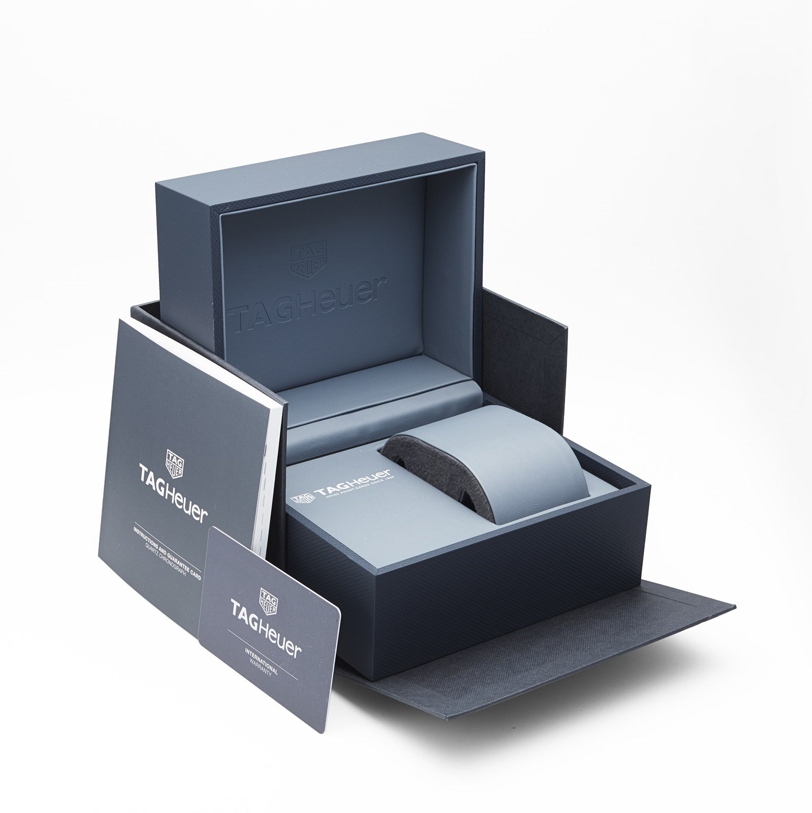 An open TAG Heuer box displays branded packaging, a cushion for your Formula 1 Date watch, a warranty card, and booklet on a white background—perfect for showcasing your TAG Heuer Formula 1 Date timepiece.