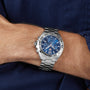 A TAG Heuer Formula 1 Chronograph watch is worn on a persons left wrist, paired with a dark blue shirt.