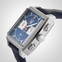 A close-up of the TAG Heuer Monaco Chronograph, featuring a square face with a blue dial, silver case, two subdials, date display, and paired with a blue leather strap.