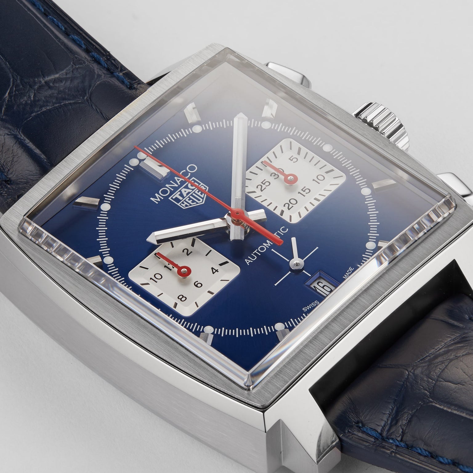 Close-up of the TAG Heuer Monaco Chronograph: square face, blue dial, two white subdials, red hands, and a blue leather strap—powered by the advanced Heuer 02 movement.