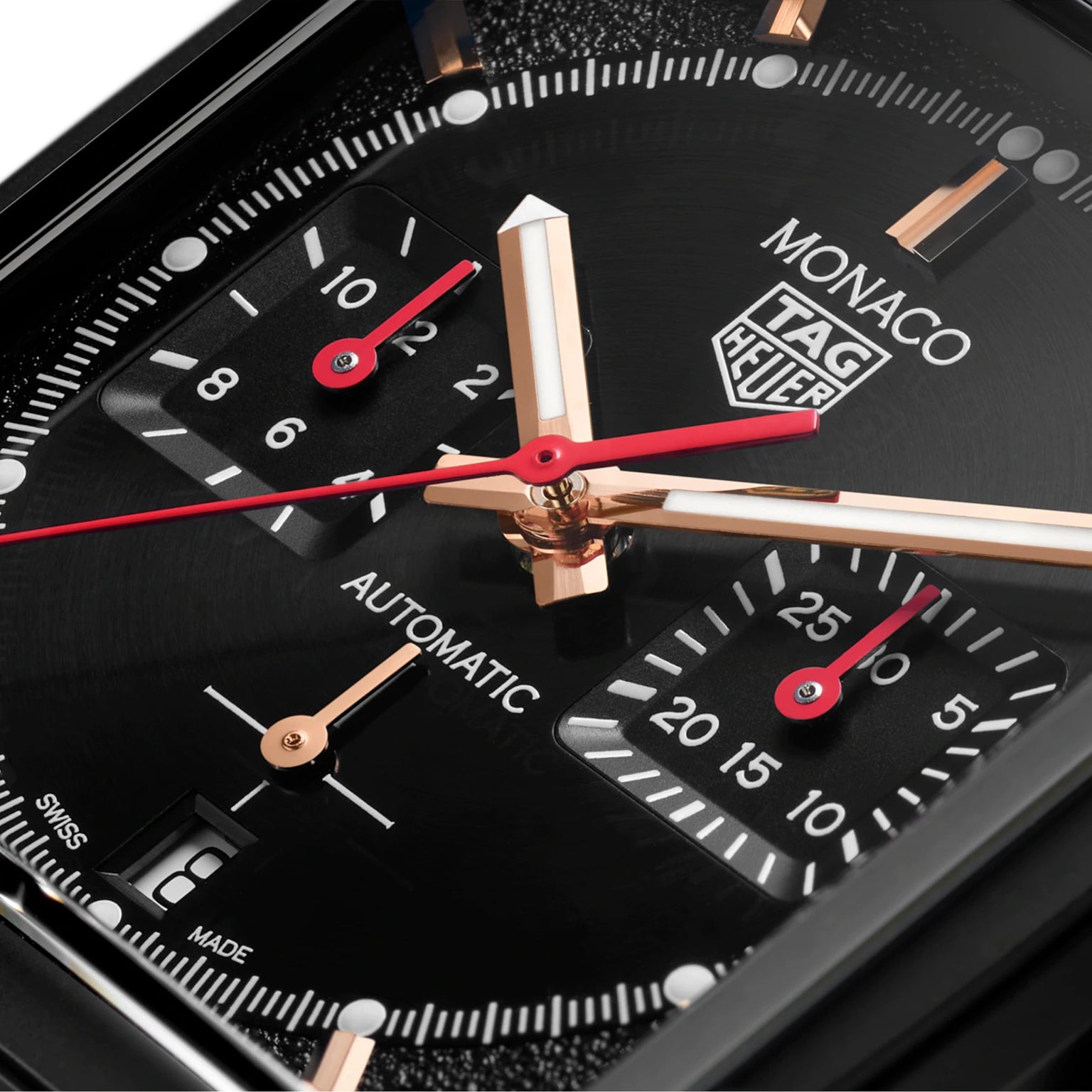 Close-up of the TAG Heuer Monaco Chronograph, showcasing a black DLC titanium face with gold-tone and red chronograph hands, square subdials, and markers on a deep black background powered by the advanced Heuer 02 movement.