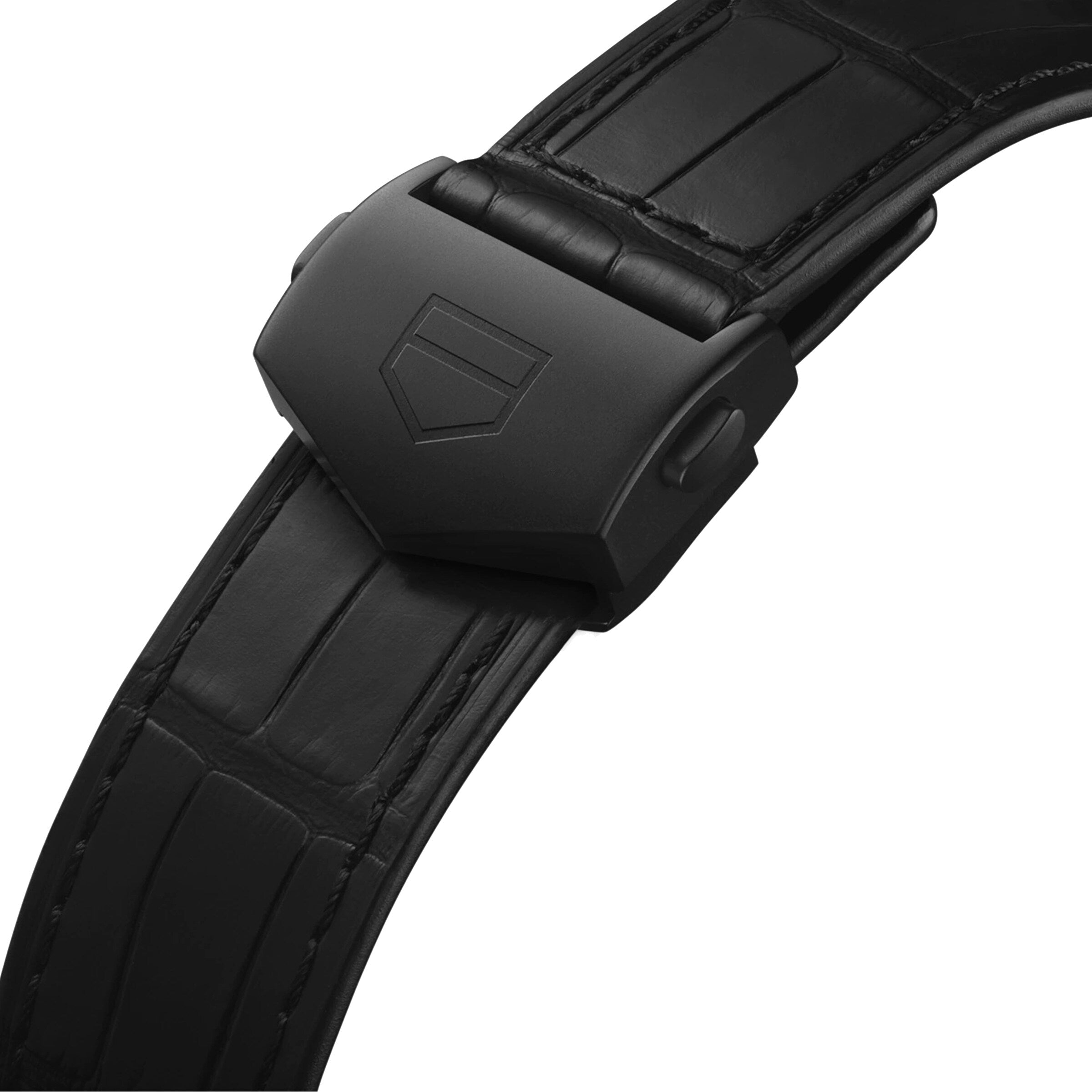 Close-up of a black leather strap with matte black DLC titanium deployment clasp, featuring an engraved shield logo, designed for the TAG Heuer Monaco Chronograph watch.