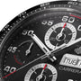 Close-up of the TAG Heuer Carrera Chronograph watch face, featuring a black ceramic bezel, three subdials, white hands, and a day-date window showing TUE 8.