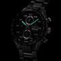A TAG Heuer Carrera Chronograph watch with luminous hands, visible subdials, a ceramic bezel, and a metal bracelet is shown against a dark background.