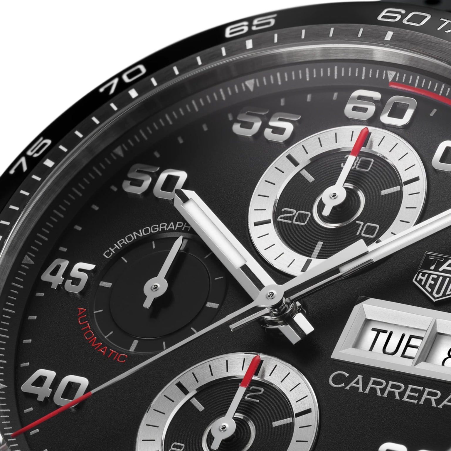 Close-up of the TAG Heuer Carrera Chronograph watch face, featuring hands, subdials, and date display. White and red numerals on black showcase its precision and endurance.