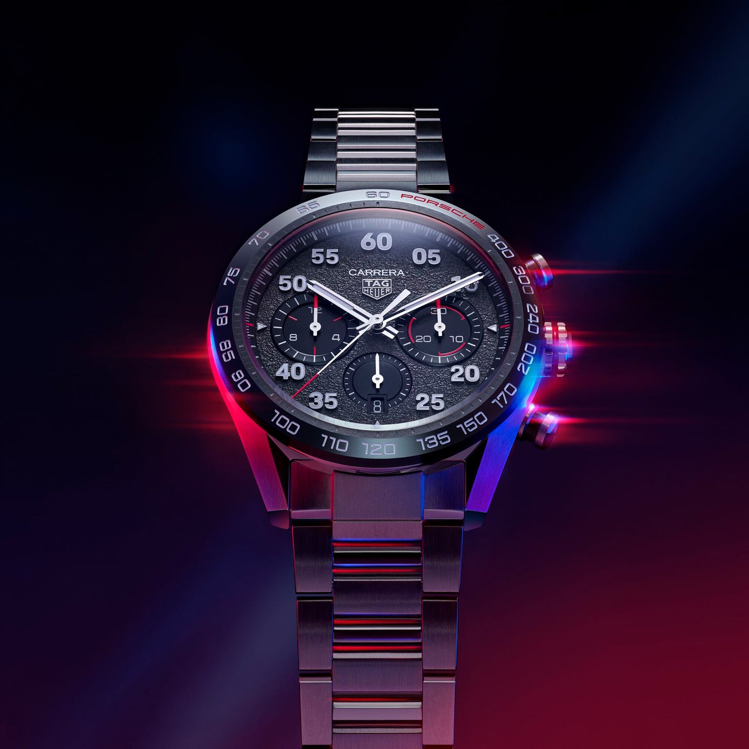 The TAG Heuer Special Edition Carrera Chronograph x Porsche features a black dial, stainless steel bracelet, and Porsche-inspired design, highlighted by striking blue and red lighting effects.