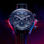A close-up of the TAG Heuer Special Edition Carrera Chronograph x Porsche wristwatch with a black strap, dramatically lit in red and blue.