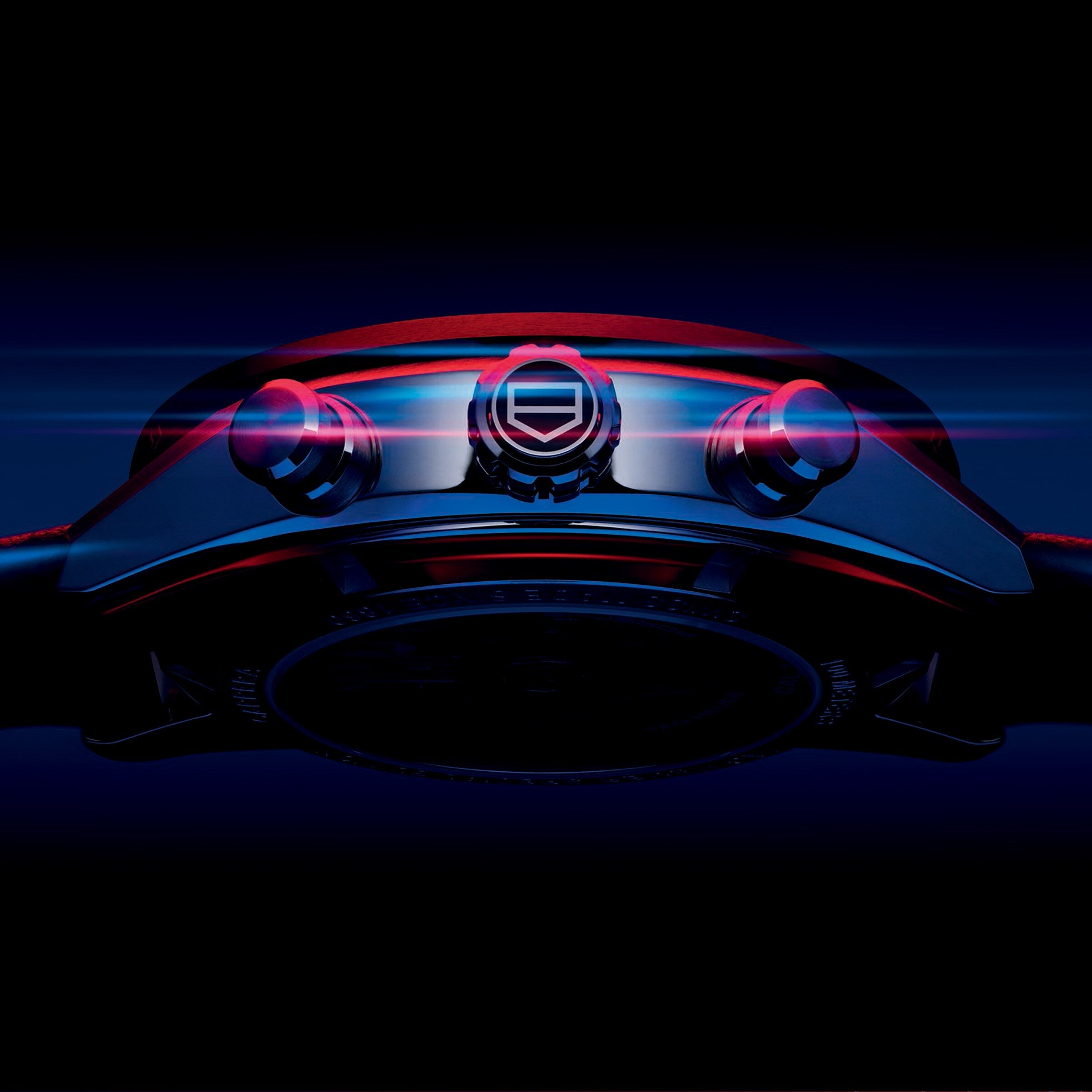 A close-up, low-angle view of the TAG Heuer Special Edition Carrera Chronograph x Porsche wristwatch with illuminated buttons and crown set against a dark, blue-black background.