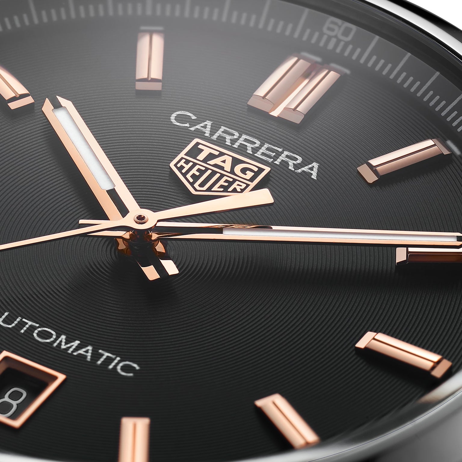 Close-up of the TAG Heuer Carrera Date watch face, featuring rose gold hour markers and hands in a sleek steel case, with Automatic labeling and part of the date window visible.