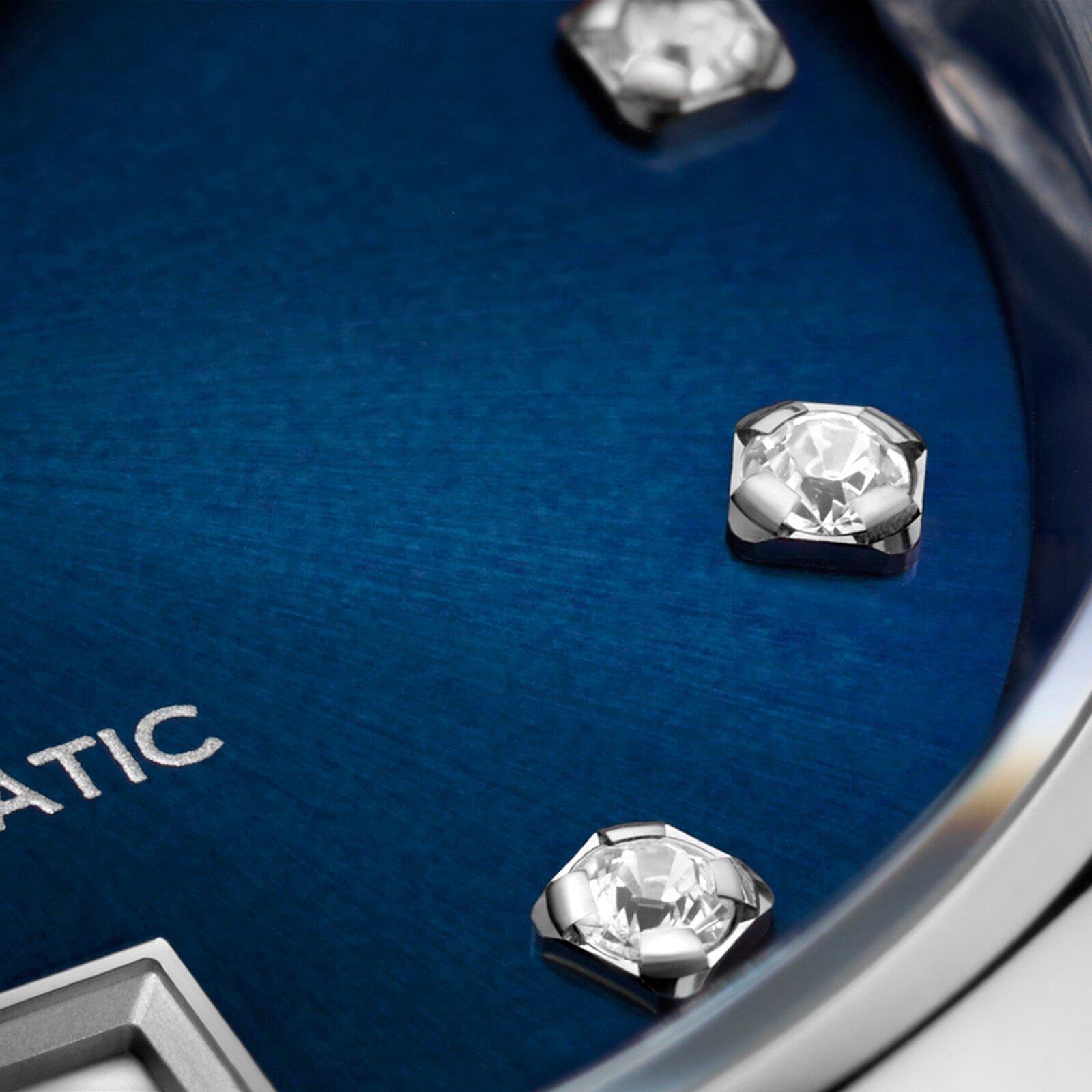 Close-up of the TAG Heuer Carrera Date watch, showcasing a blue sunray dial with diamond hour markers and a partial view of the silver AUTOMATIC inscription.