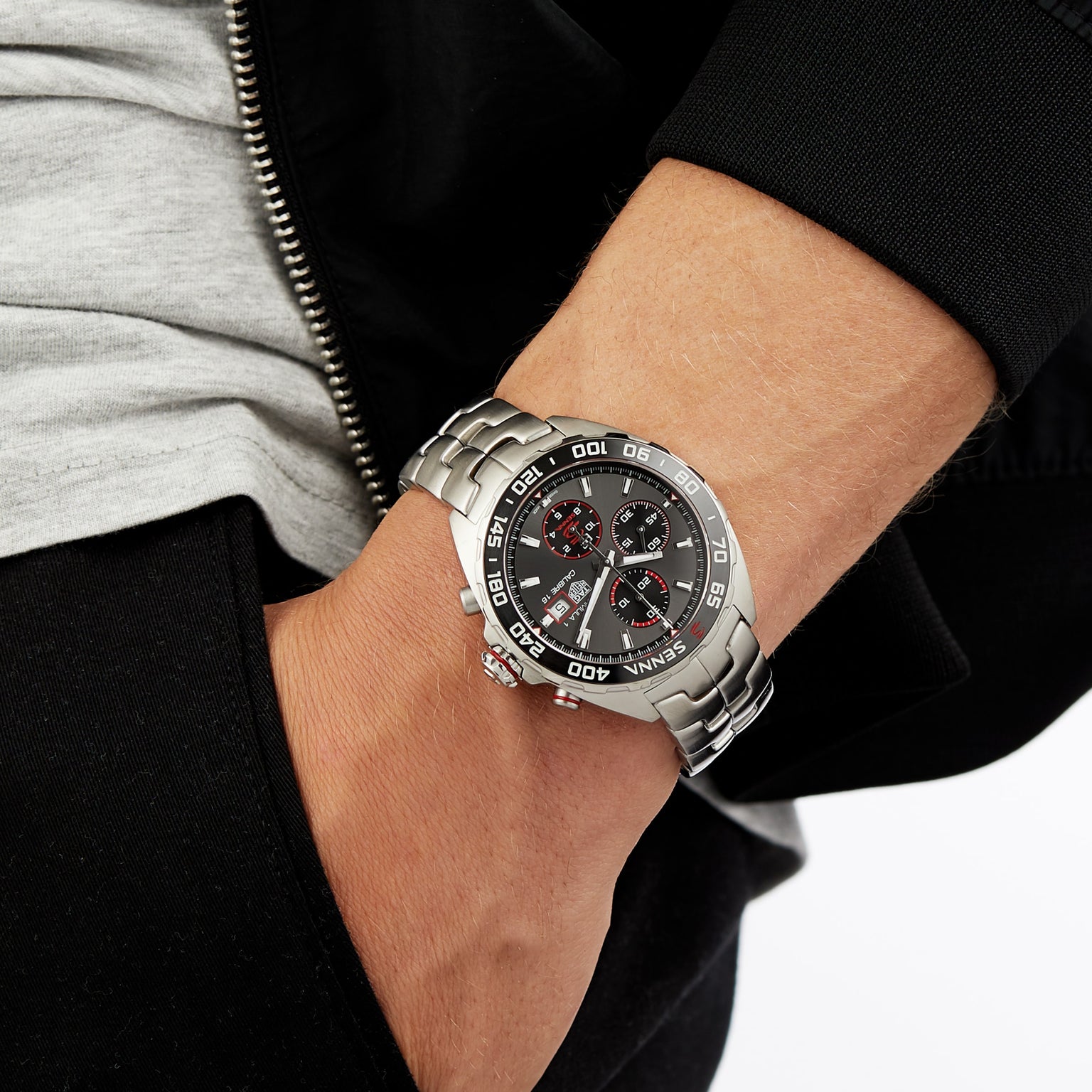 A TAG Heuer Special Edition Formula 1 Senna chronograph watch with a black dial and red accents on a person’s wrist, hand in pocket.