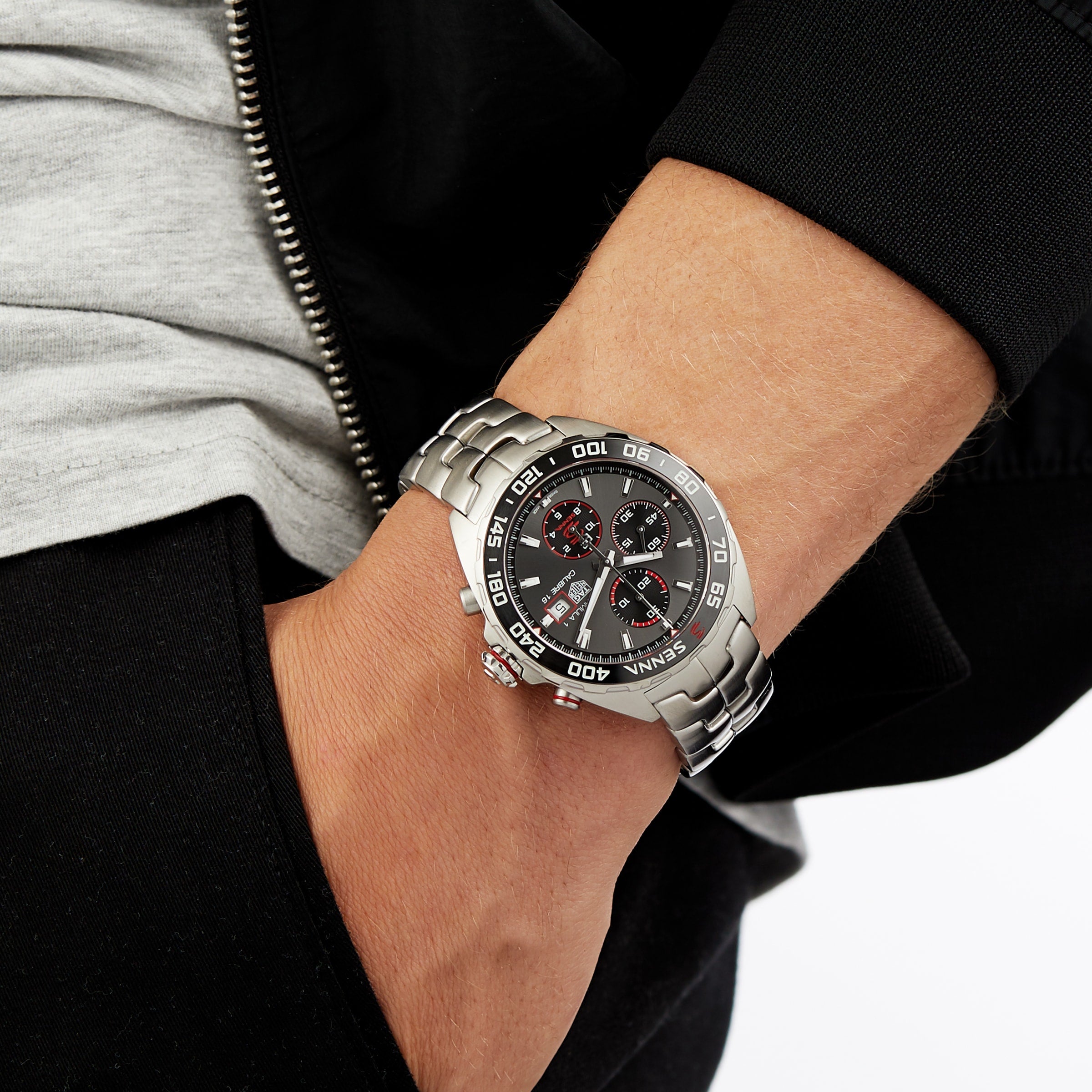 A TAG Heuer Special Edition Formula 1 Senna chronograph watch with a black dial and red accents on a person’s wrist, hand in pocket.