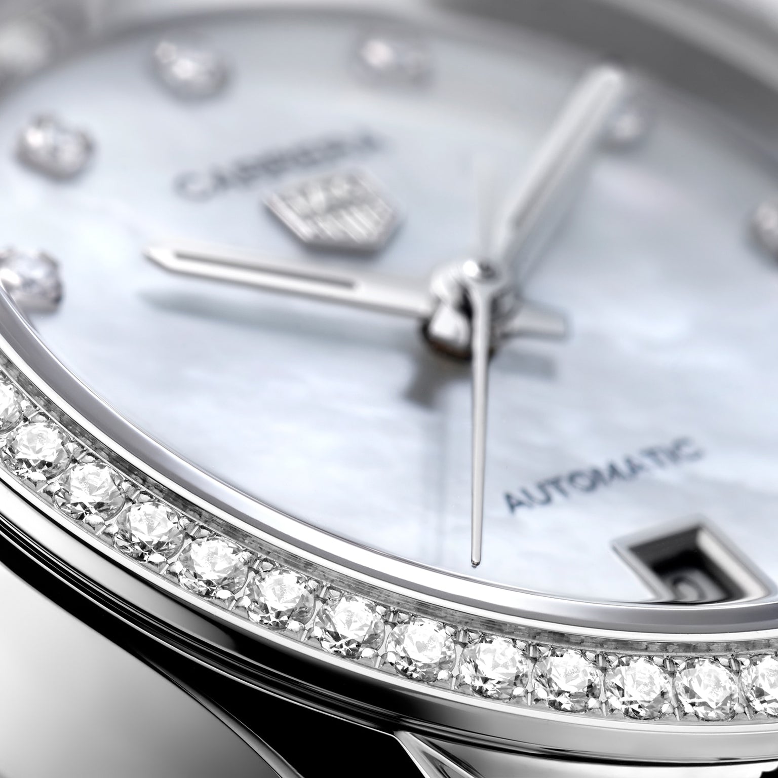 Close-up of a TAG Heuer Carrera Date wristwatch featuring a diamond bezel, silver hands, and a date window on a white dial marked with Carrera and Automatic.