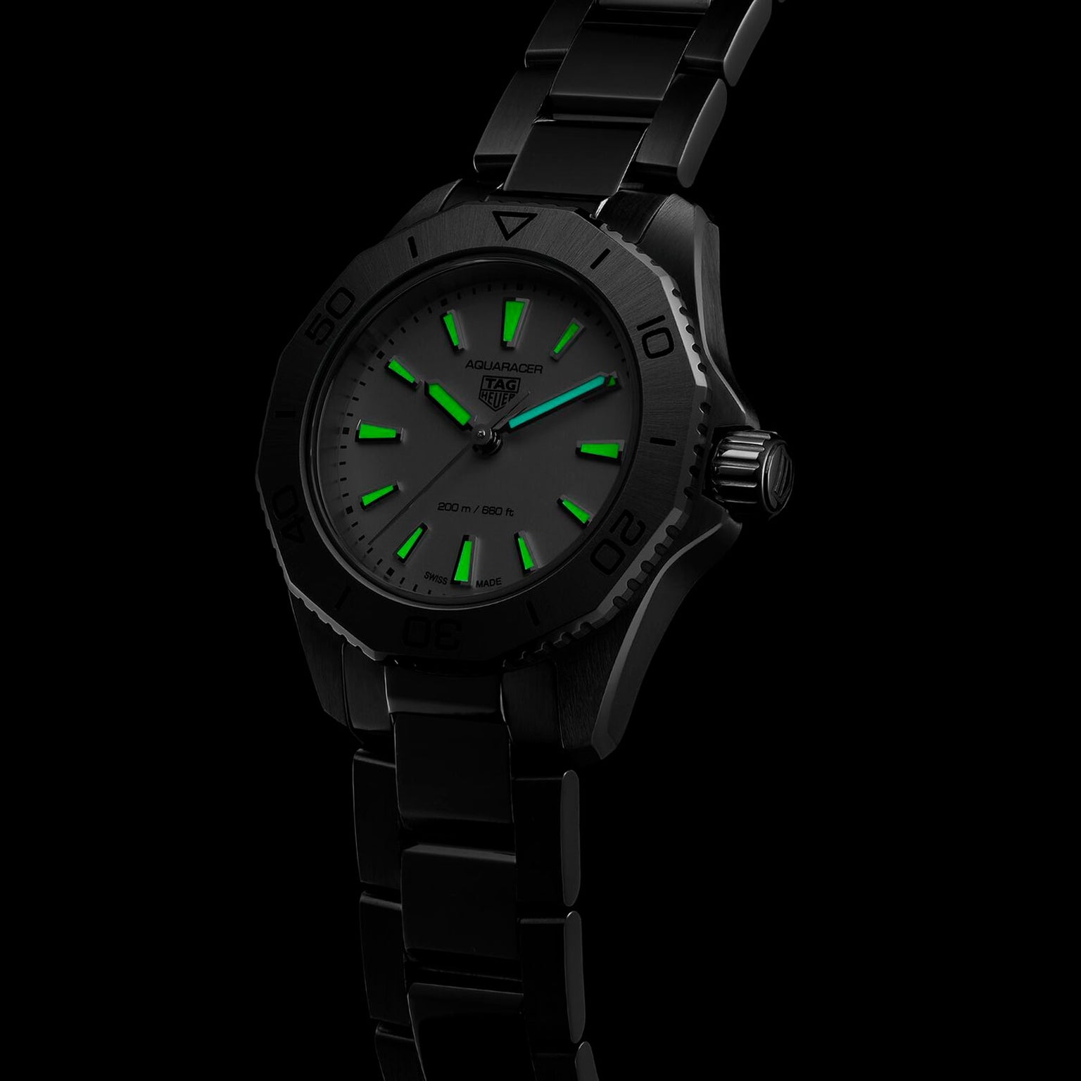 A TAG Heuer Aquaracer Professional 200 sports watch with a black stainless steel case and glowing green hour markers and hands is displayed against a dark background.