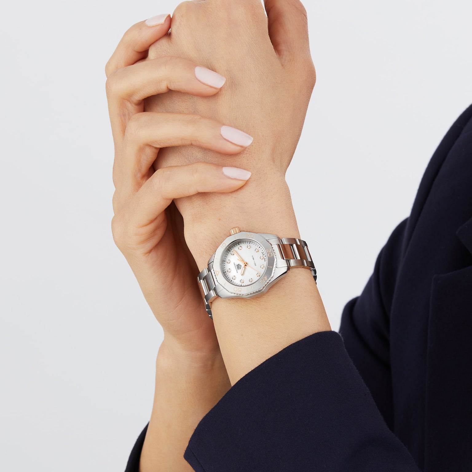 A person in a dark sleeve holds their wrist with the other hand, wearing a TAG Heuer Aquaracer Professional 200 featuring a round face and stainless steel case.