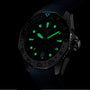 The TAG Heuer Aquaracer Professional 300 GMT sports watch features a black dial with luminous green hands and hour markers, glowing brightly in low-light conditions.