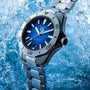 The TAG Heuer Aquaracer Professional 200 Date, featuring a stainless steel case and blue dial, is displayed against an icy backdrop.