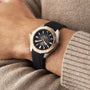Someone wearing a TAG Heuer Aquaracer Professional 200, featuring a black and gold case with a rubber strap, rests their hand on a beige knitted sweater.