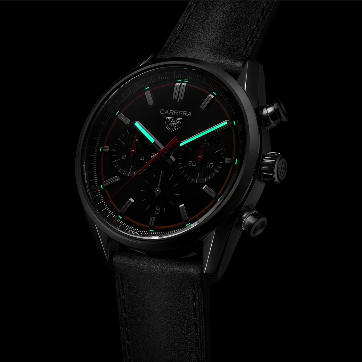 The TAG Heuer Carrera Chronograph features a black dial, two subdials, luminous green hands and markers, a Calibre HEUER 02 movement, and a black leather strap.