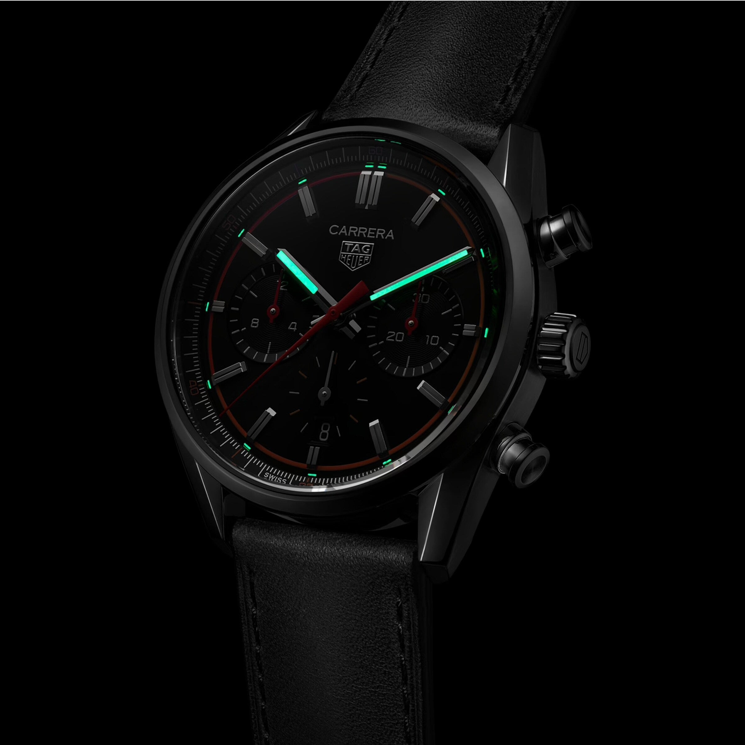 The TAG Heuer Carrera Chronograph features a black dial, two subdials, luminous green hands and markers, a Calibre HEUER 02 movement, and a black leather strap.