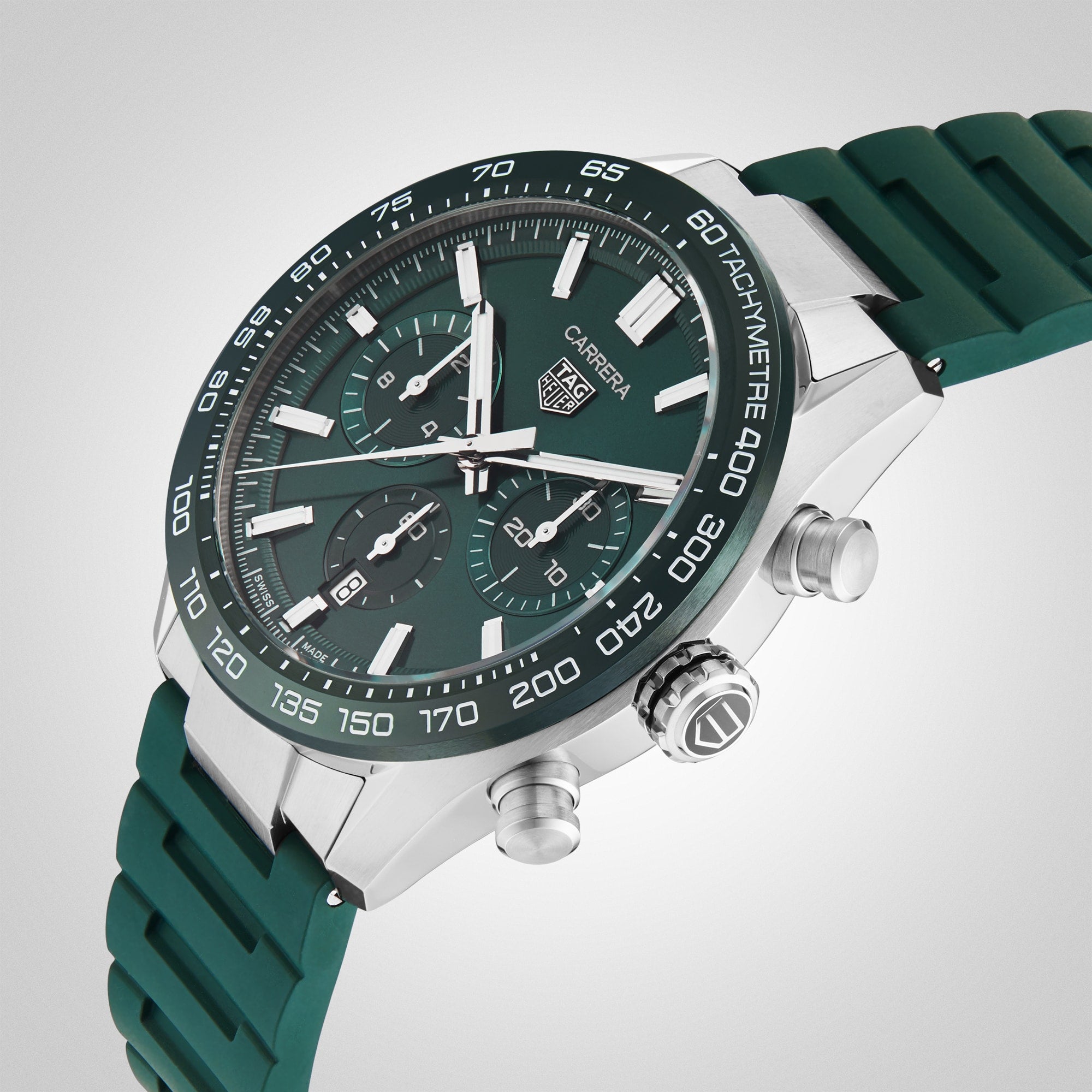 The TAG Heuer Carrera Chronograph features a green dial, green rubber strap, silver case, and three subdials. Powered by the precise Heuer 02 calibre, it celebrates motor-racing heritage on a light gradient background.