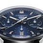 Close-up of a TAG Heuer Carrera Chronograph watch, featuring a blue dial, silver markers and hands, chronograph subdials, Calibre TH20-00 movement, and a date window at 6 o’clock.