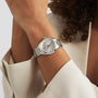 Wearing a light-colored blazer, one exudes elegance while showcasing the TAG Heuer Carrera Date silver wristwatch with a white face and date display.