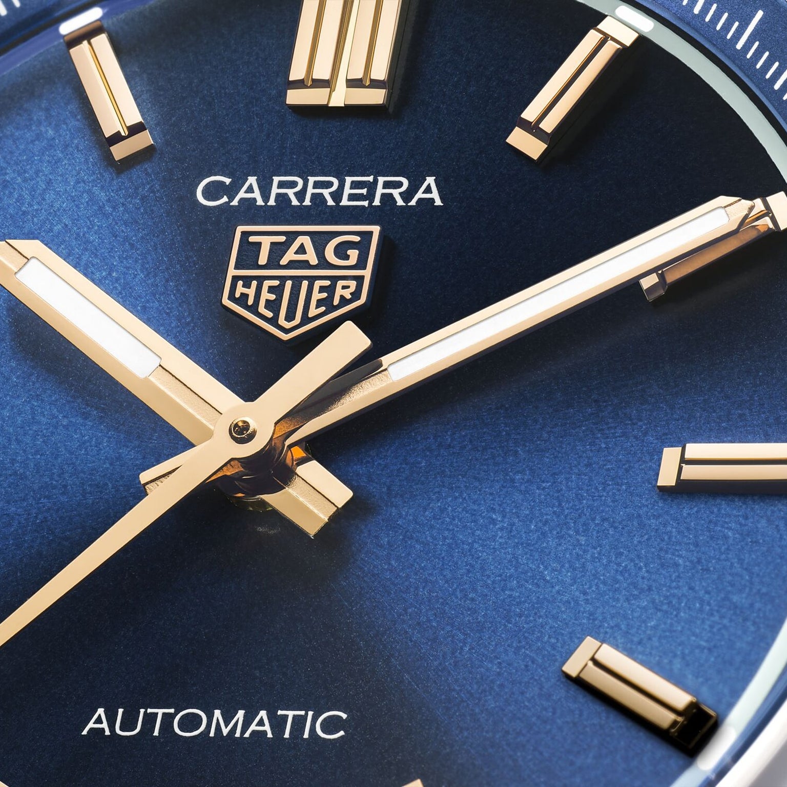 Close-up of the TAG Heuer Carrera Date watch face in blue, featuring gold hour markers and hands that combine elegance with enduring style.