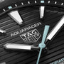 Close-up of the TAG Heuer Aquaracer Professional 200 Solargraph watch face, featuring the brand logo, luminescent hour markers and hands on a textured black dial, highlighting the precision and style of this solar-powered timepiece.