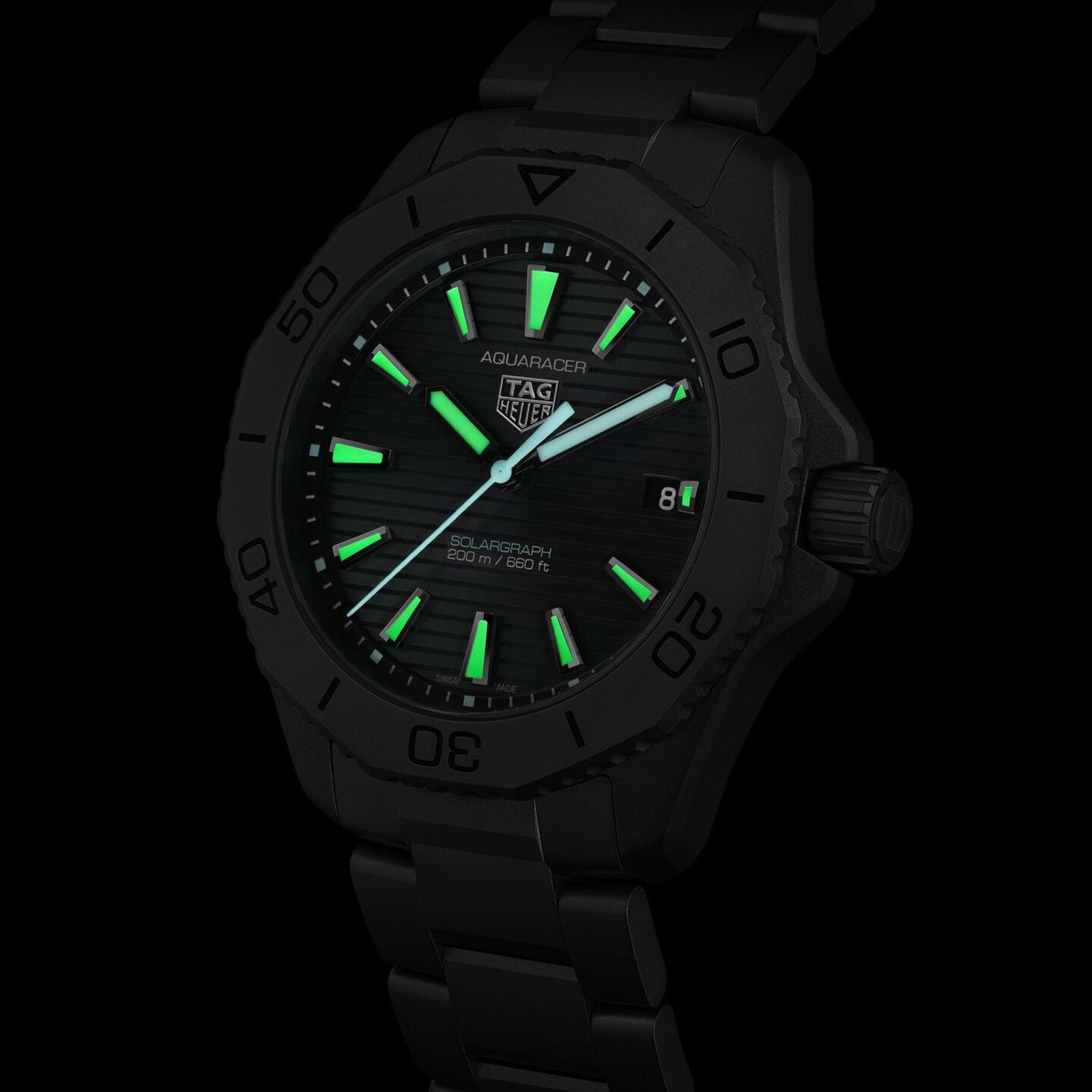 The TAG Heuer Aquaracer Professional 200 Solargraph features a black case, glowing green dial and markers, and a date at 3 o’clock. This solar-powered watch stands out against a black background, blending bold style with innovation.