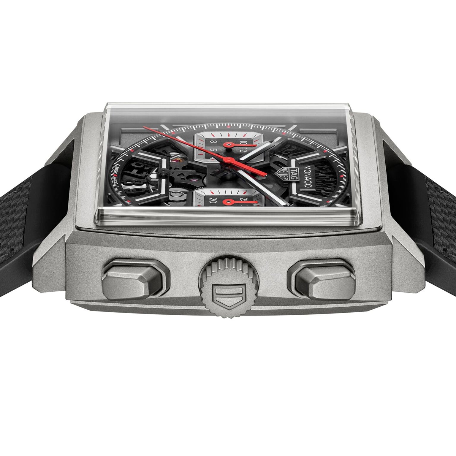Close-up of the TAG Heuer Monaco Chronograph, featuring a square case, skeletonised dial with red accents, black textured strap, and visible crown with two pushers.