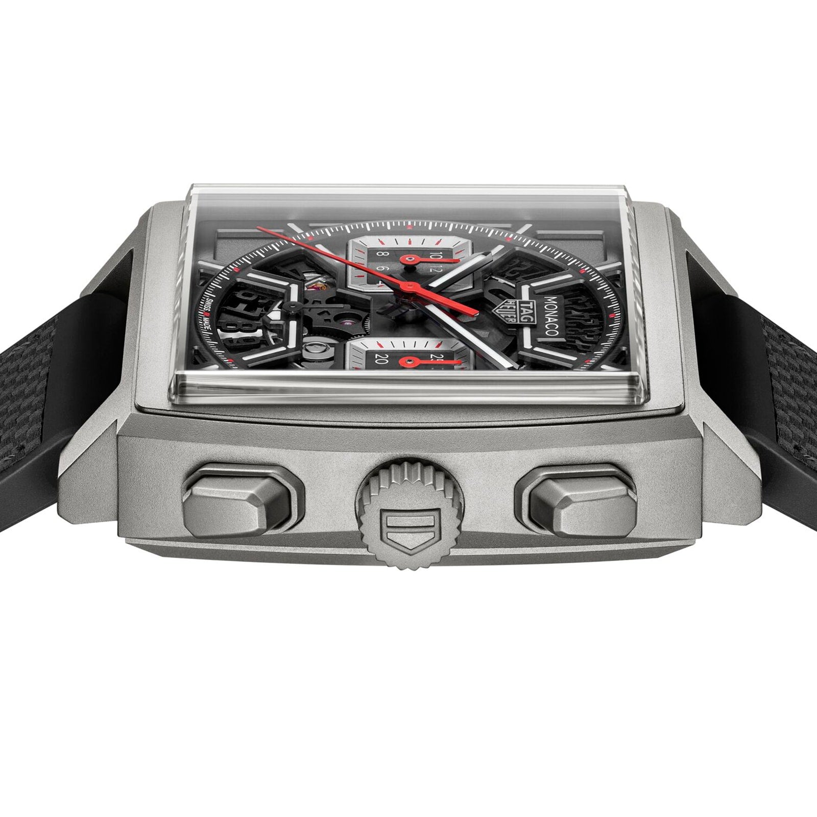 Close-up of the TAG Heuer Monaco Chronograph, featuring a square case, skeletonised dial with red accents, black textured strap, and visible crown with two pushers.