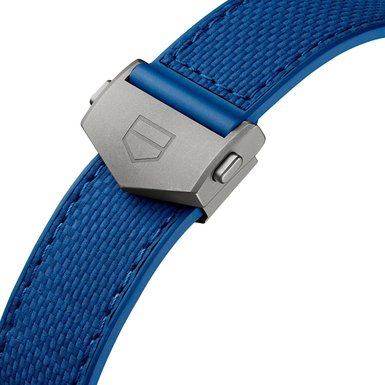 Close-up of a blue textured TAG Heuer Monaco Chronograph watch strap with a silver clasp engraved with the shield logo.