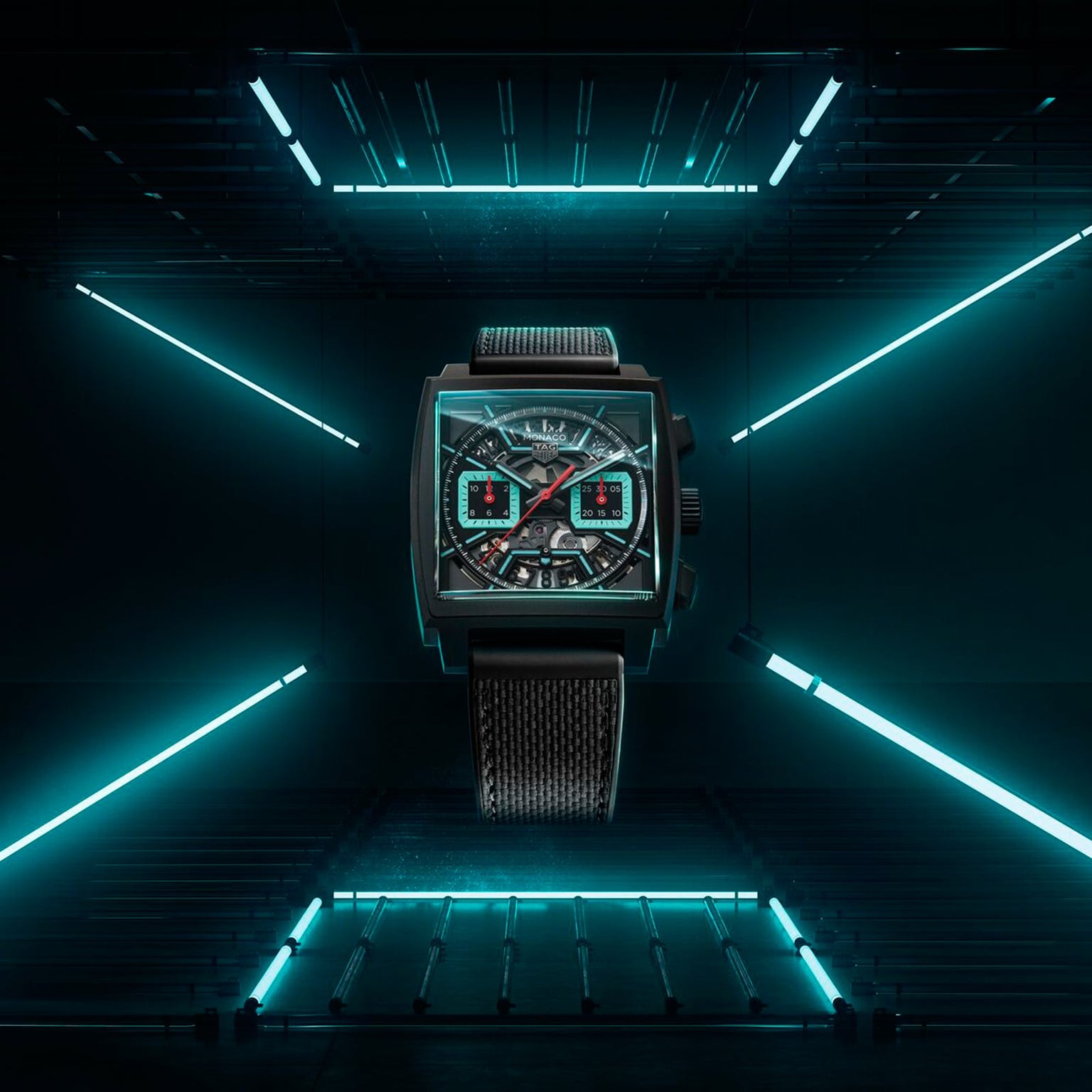 A TAG Heuer Monaco Chronograph with a square face and black strap is showcased in a futuristic dark setting under blue neon lights.