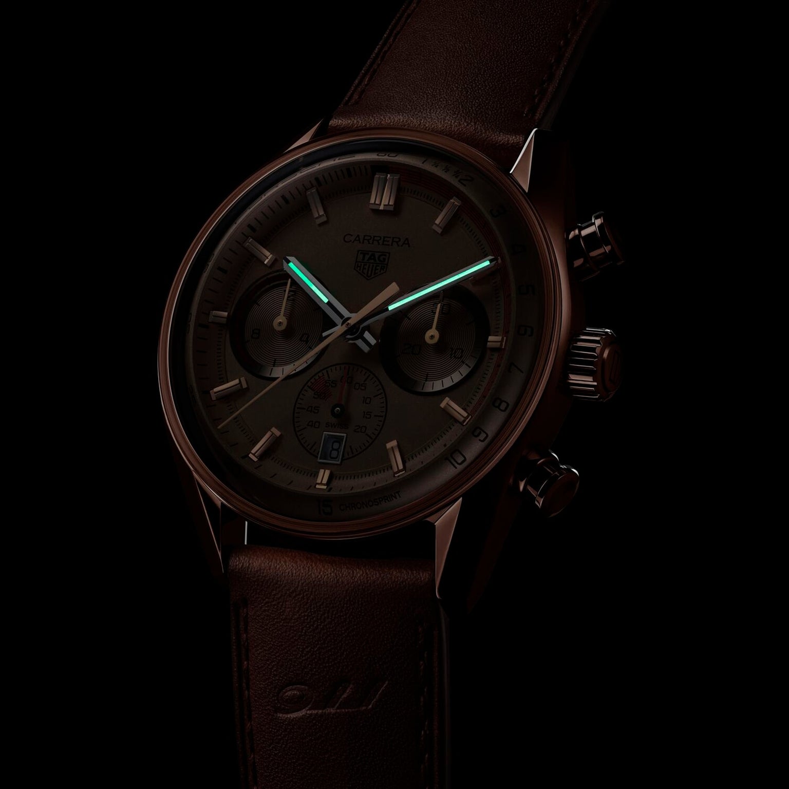 A dark-toned image of the TAG Heuer Special Edition Carrera Chronosprint x Porsche shows its leather strap and chronograph hands, powered by an automatic movement, partially illuminated with a green glow.