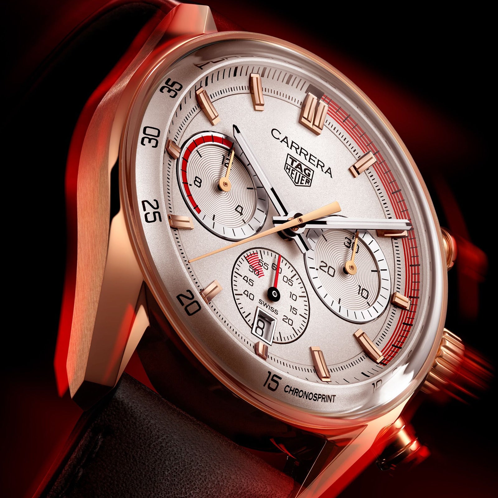 Close-up of the TAG Heuer Special Edition Carrera Chronosprint x Porsche, featuring a rose gold case, white dial with chronograph subdials, and a black leather strap—highlighting its automatic movement—against a dark red background.