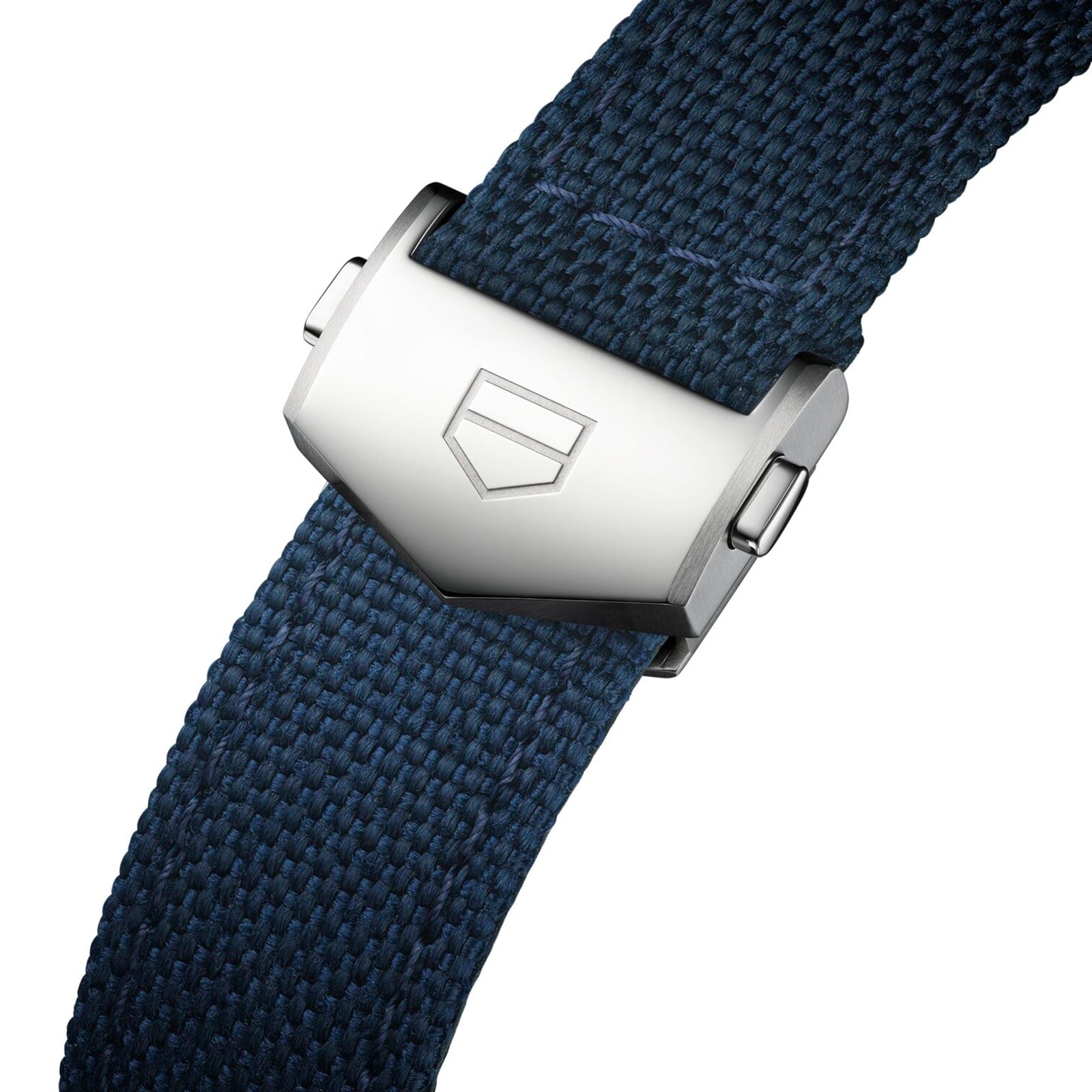 Close-up of a silver metal clasp featuring TAG Heuer’s geometric logo, securing a blue textured strap on the Carrera Chronograph Skipper—reflecting the bold design and racing spirit of Carrera.