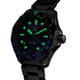 The TAG Heuer Aquaracer Professional 300 GMT watch features glowing green markers and hands, shown from an angle.