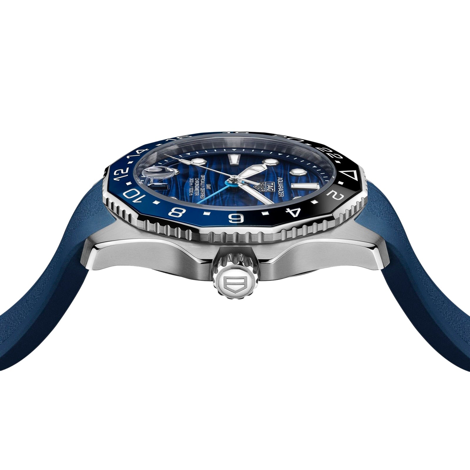 A close-up side view of the TAG Heuer Aquaracer Professional 300 GMT, featuring a blue dial, black and blue bezel, and blue rubber strap, showcasing the crown, case profile, and automatic movement.