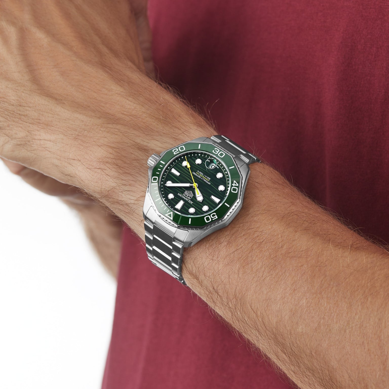 Someone adjusts the TAG Heuer Aquaracer Professional 300 Date, featuring a green ceramic bezel and stainless steel strap, on their wrist.