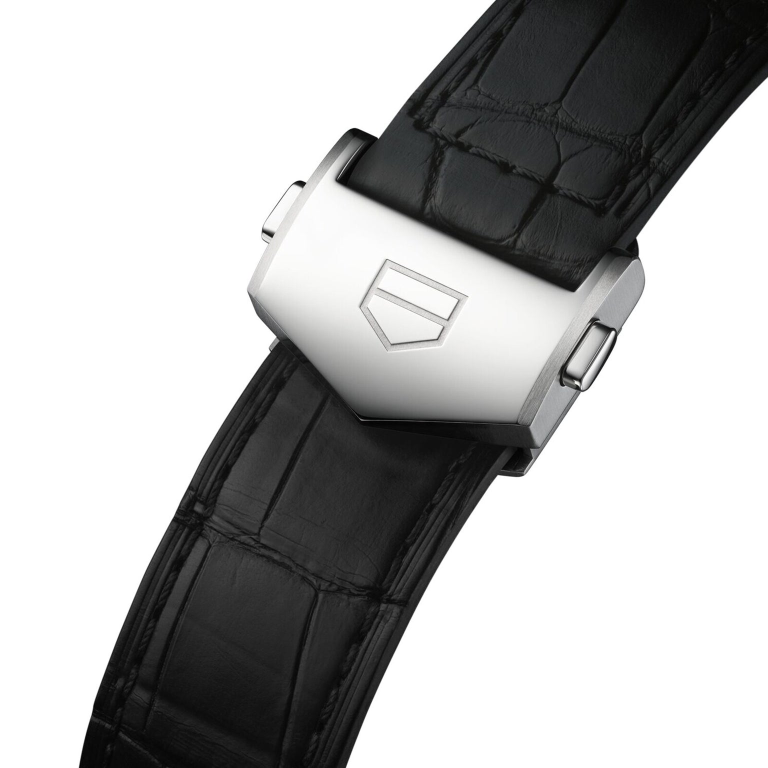 Close-up of a TAG Heuer Carrera Chronograph’s black leather strap with silver deployment clasp, engraved shield emblem, inspired by the Carrera Panamericana and fitted to a model with TH20-07 automatic movement.