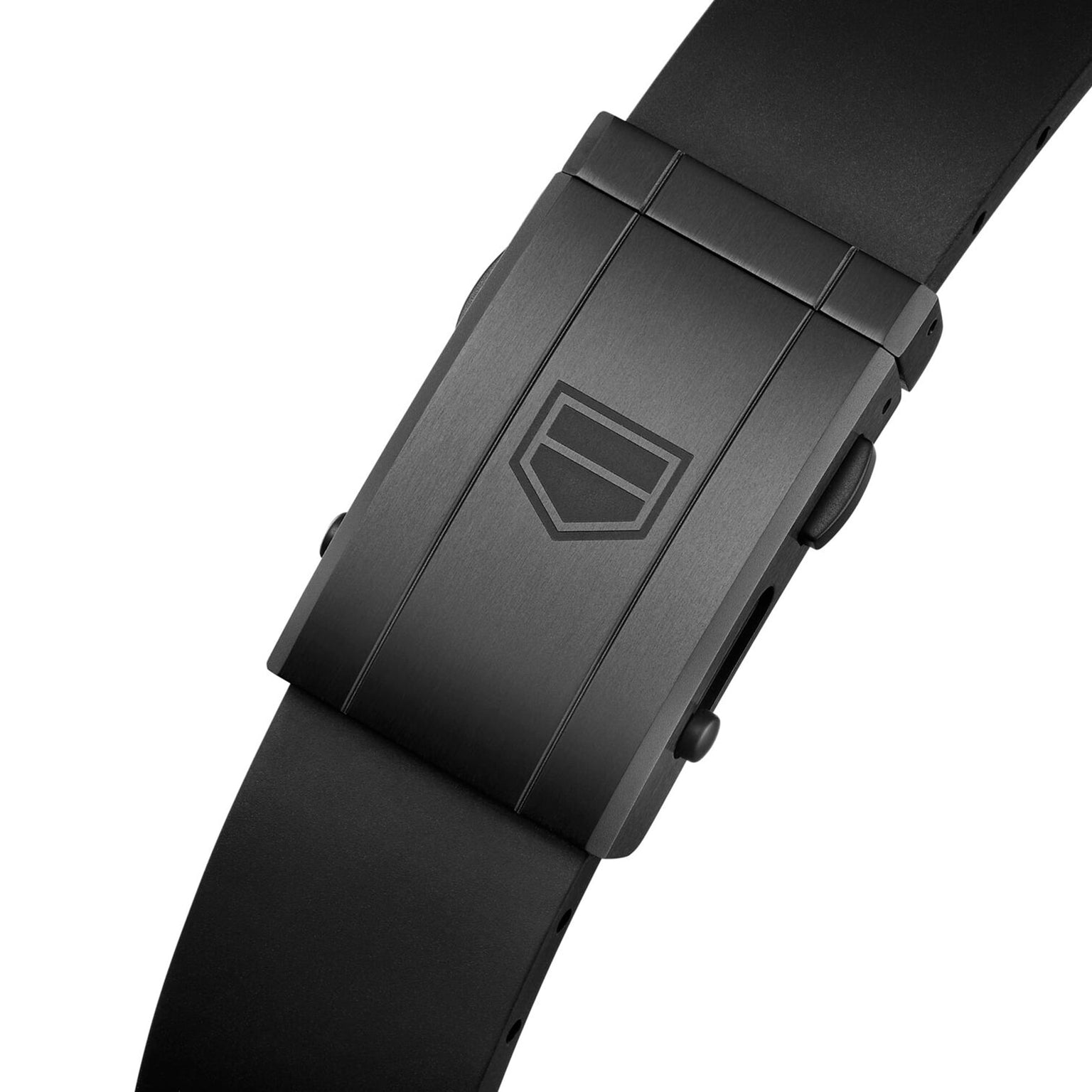 Close-up of a black metal clasp with an engraved shield logo on a black silicone strap—an elegant detail on the TAG Heuer Carrera Chronograph Extreme Sport.