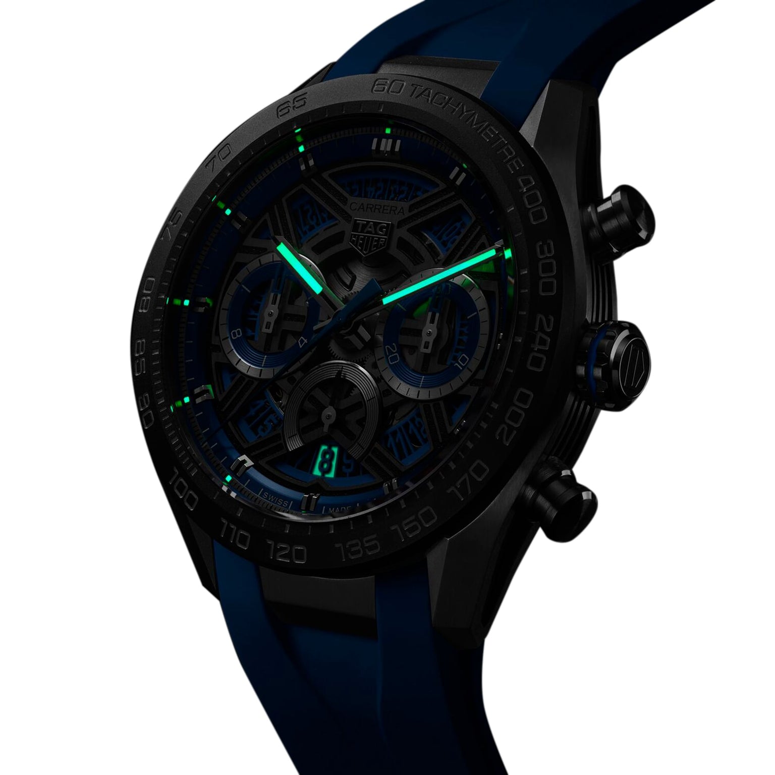 The TAG Heuer Carrera Chronograph Extreme Sport wristwatch, in black and blue, features luminous green hands and hour markers, shown glowing in low light.