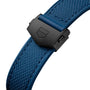 Close-up of a blue textured watch strap with a black clasp featuring a geometric logo, perfectly paired with TAG Heuer’s iconic square Monaco Chronograph case.
