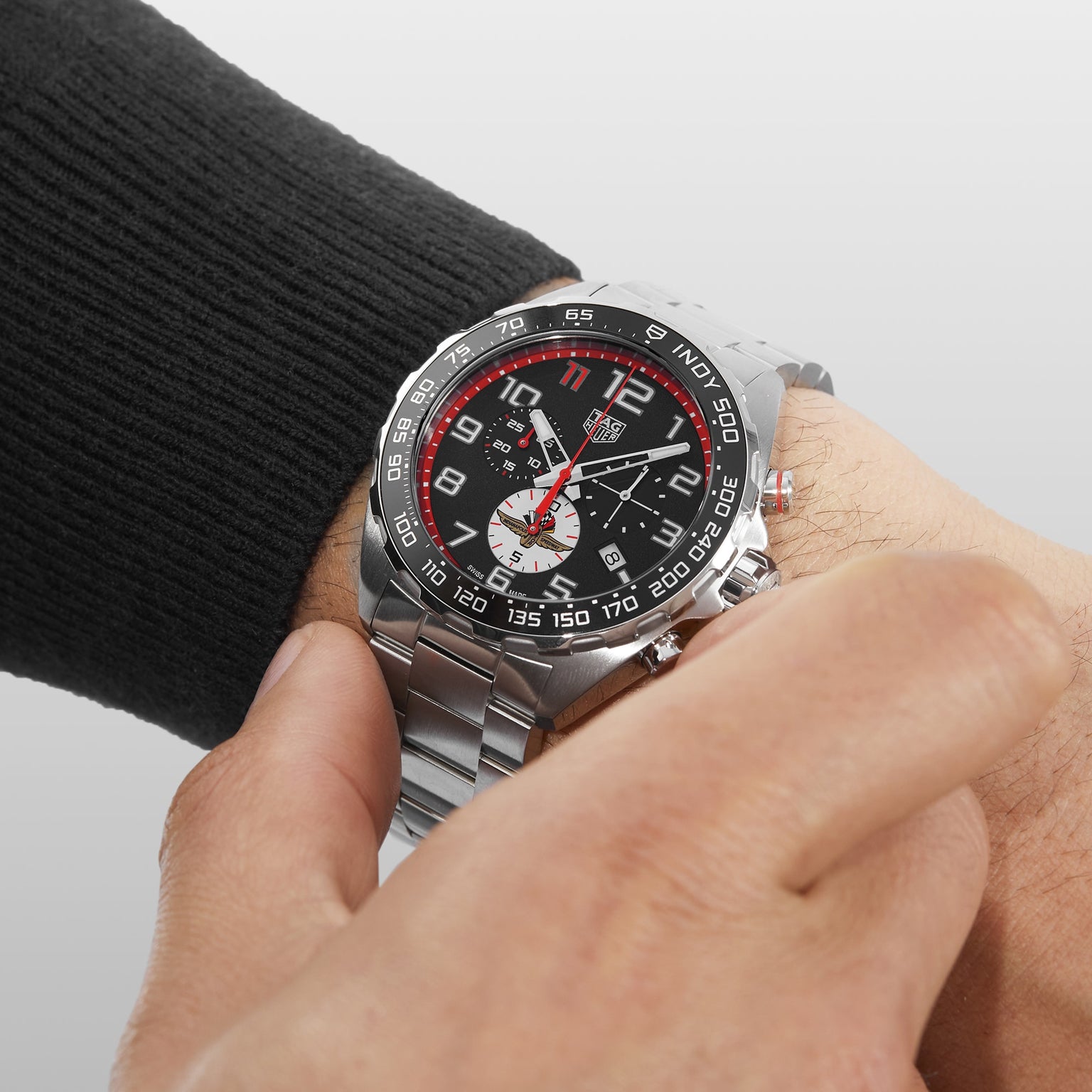 A person adjusts the crown of their TAG Heuer Special Edition Formula 1 X Indy 500 chronograph, featuring a black and red dial.
